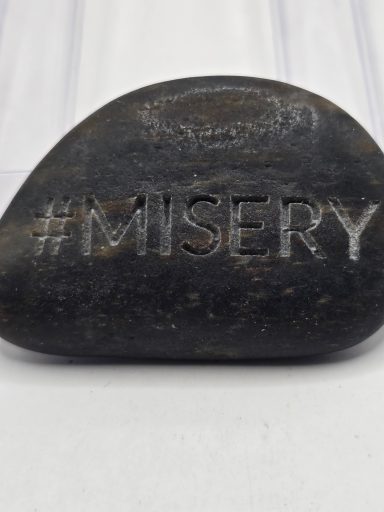 laser engraved river rock with word misery